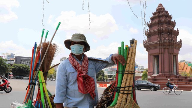 រូបតំណាង៖ បុរសអ្នកលក់អំបោស ដោយមានពាក់ម៉ាស់ផង កំពុងដើរតាមផ្លូវព្រះនរោត្តម ក្នុងរាជធានីភ្នំពេញ រូបភាព៖ Xinhua