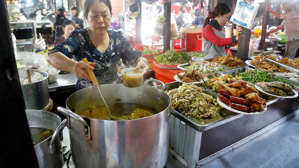 អាជីវករលក់បាយម្ហូបនៅទីផ្សាយមួយកន្លែងក្នុងរាជធានីភ្នំពេញ រូបភាព៖ Xinhua