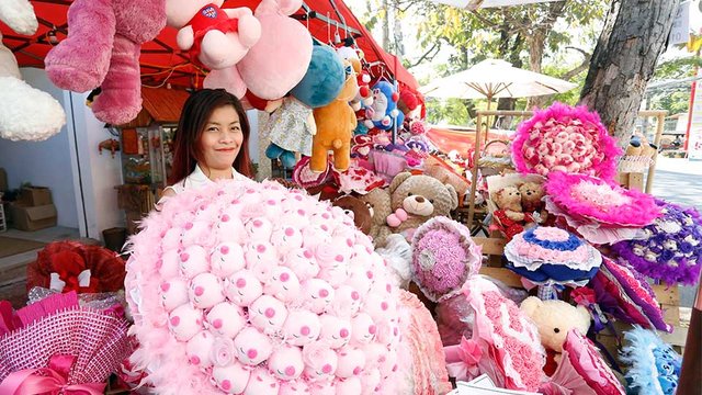 ស្ត្រី​វ័យ​ក្មេង​រៀបចំ​កន្លែង​តាំង​លក់​កាដូ ឬ​អំណោយ​ដែល​យុវជន​និយម​ទិញ​ក្នុង​ថ្ងៃ​បុណ្យ​នៃ​ក្ដី​ស្រលាញ់។